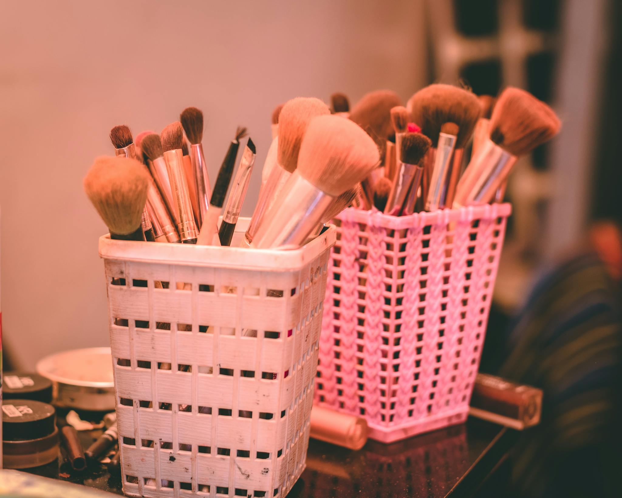 Collection of various makeup brushes organized neatly in pink and white holders.